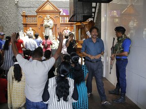 A Sri Lankan naval soldier stands guard as Catholic devotees pray at the St. Anthony's church after it was partially opened for the first time since Easter Sunday attacks, in Colombo, Sri Lanka, Tuesday, May 7, 2019. Two bomb experts were among the suicide attackers who struck churches and hotels on Easter in Sri Lanka and all those directly involved in the bombings are either dead or under arrest, police said.