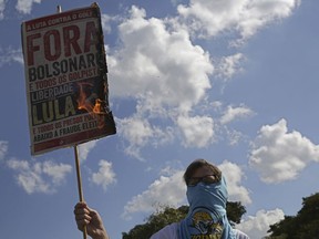A masked student burns a poster with a message that reads in Portuguese: "Out Bolsonaro" during an education strike in Brasilia, Brazil, Wednesday, May 15, 2019. Federal education officials this month announced budget cuts of $1.85 billion for public education, part of a wider government effort to slash spending.