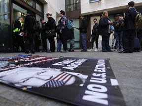 A poster lays on the pavement as supporters and journalists queue at the entrance of Westminster Magistrates Court in London, Thursday, May 2, 2019, where WikiLeaks founder Julian Assange is expected to appear by video link from prison.  Assange is facing a court hearing over a U.S. request to extradite him for alleged computer hacking.