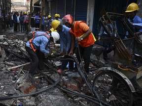 Bangladeshi firefighters cut burnt electric lines after a fire tore through apartment blocks in Bangladesh's capital Dhaka on February 21, 2019. At least 70 people were killed when fire tore through crumbling apartment blocks in a historic part of Dhaka, setting off a chain of explosions and a wall of flames down nearby streets, officials said on February 21.