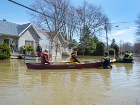 Quebec Provincial Police officers escort evacuees to retrieve belongings from their flooded homes on Monday, April 29, 2019 in Ste.Marthe-sur-la-Lac, Que.