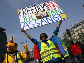 A man wearing a yellow vest holds a banner reading "Freedom for Julian Assange", during a May Day demonstration in Paris, Wednesday, May 1, 2019. French authorities announced tight security measures for May Day demonstrations, with the interior minister saying there was a risk that "radical activists" could join anti-government yellow vest protesters and union workers in the streets of Paris and across the country.