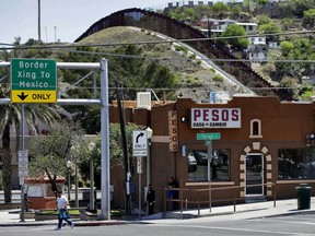FILE - In this April 10, 2018, file photo, the International border cuts through Nogales, Sonora, Mexico, rear, as seen from Nogales, Ariz. Federal court records say a Border Patrol agent in Arizona sent texts referring to migrants as "savages" and "subhuman" the month before allegedly knocking over a Guatemalan man with his patrol vehicle. The filings in U.S. District Court in Tucson earlier in May 2019 say Agent Matthew Bowen sent the text messages in November 2017, weeks before allegedly knocking down the migrant. He goes on trial Aug. 13. He has pleaded not guilty to depriving the migrant of his rights and falsifying records.