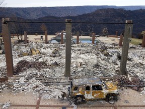File - In this Dec. 3, 2018, file photo, a vehicle rests in front of a home leveled by the Camp Fire in Paradise, Calif. A federal judge on Tuesday, May 7, 2019, ordered board members of Pacific Gas & Electric to tour the Northern California town of Paradise, which was leveled by a wildfire that may have been caused by the utility's equipment. The judge ordered the tour as part of the utility's punishment for violating its felony probation terms, reported the San Francisco Chronicle.