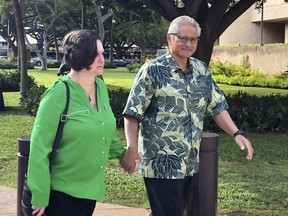 FILE - In this March 12, 2019 file photo, retired Honolulu police chief Louis Kealoha and his wife, former deputy city prosecutor Katherine Kealoha, hold hands while walking to U.S. district court in Honolulu. Opening statements are expected Wednesday, May 22, 2019, after 12 jurors and five alternates are selected for the trial of retired Honolulu police chief Louis Kealoha, his wife and current and former officers. Prosecutors say Kealoha and his former city deputy prosecutor wife, Katherine Kealoha, abused their power to frame a relative for stealing their home mailbox because he threatened to expose financial fraud that funded the couple's lavish lifestyle.
