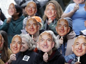 In this Oct. 31, 2018, file photo, demonstrators hold images of Amazon CEO Jeff Bezos near their faces during a Halloween-themed protest at Amazon headquarters over the company's facial recognition system, "Rekognition," in Seattle.