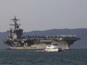 A Vietnamese passenger boat sails on March 2, 2018, past U.S. aircraft carrier USS Carl Vinson as it docks in Danang bay, Vietnam.