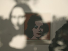 In this photo taken Wednesday, May 15, 2019, in a display of female icons, Elizabeth Taylor is reflected in an image of the Mona Lisa at the exhibition, "Andy Warhol _ From A to B and Back Again" in San Francisco. A retrospective of Andy Warhol's work on display at the San Francisco Museum of Modern Art captures his use of artwork to give his subjects personas the way people do now using social media.