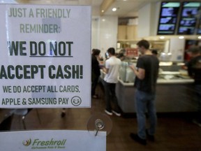 This Thursday, May 2, 2019, photo shows a sign posted on a door alerting customers that cash is not accepted at Freshroll Vietnamese Rolls and Bowls in San Francisco. San Francisco is about to require brick-and-mortar retailers to take cash in payment for goods, joining Philadelphia and New Jersey in banning a practice that critics say discriminates against the poor.