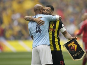 Manchester City's Vincent Kompany, left, hugs Watford's Troy Deeney before the English FA Cup Final soccer match between Manchester City and Watford at Wembley stadium in London, Saturday, May 18, 2019.