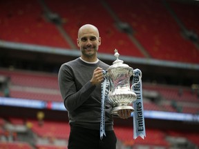 Manchester City's manager Pep Guardiola poses for a picture as lifts the trophy after winning the English FA Cup Final soccer match between Manchester City and Watford at Wembley stadium in London, Saturday, May 18, 2019. Manchester City won 6-0.