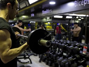 In this Sunday, May 26, 2019 photo, a Palestinian lifts weights at Techno-Gym in Gaza City. The Gaza Strip has a booming nocturnal gym scene that comes alive past midnight during the holy Islamic month of Ramadan, catering to Palestinians ready to reform their Ramadan routine. Besides self-discipline and prayer intended to bring adherents closer to God, the month is famed for its lavish meals and heavy desserts that follow a daylong fast, fueling weight-gain concerns among a growing group of middle-class men in the Palestinian enclave.