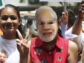 A supporter of India's ruling Bharatiya Janata Party wearing a mask of Indian Prime Minister Narendra Modi shows victory sign as they celebrate early lead in at party's state head quarter in Hyderabad, India, Thursday, May 23, 2019. Modi and his party were off to an early lead as vote counting began Thursday following the conclusion of the country's 6-week-long general election, sending the stock market soaring in anticipation of another five-year term for the Hindu nationalist leader.