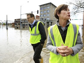 Iowa Gov. Kim Reynolds, right stops to talk with the media near the intersection of Pershing Ave. and E 2nd St. in downtown Davenport, Iowa during a tour of flooded areas of the community Friday, May 3, 2019.
