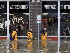 Davenport firefighters move building to building checking for people trapped after the floodwall failed at River Drive and Pershing Avenue sending Mississippi River floodwater into several blocks of downtown Davenport, Iowa Tuesday, April 30, 2019.