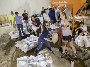 In a Wednesday, May 29, 2019 photo, volunteers fill and stack sandbags for the Monroe County Emergency Management Agency in Valmeyer, Ill. If needed the sandbags will be used to raise levee low spots and to help with sand boils. On June 4, it's expected to crest at 45.2 feet. Monroe County Sheriff Neal Rohlfing said Tuesday that if the level reaches 46 feet, he will ask all residents in the floodplain to evacuate. The historic 1993 crest was 49.58 in St. louis.