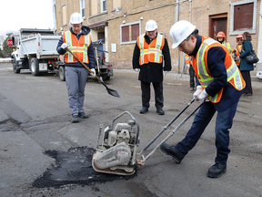 Infrastructure Minister François-Philippe Champagne, right, repairs a pothole in Sudbury, Ont. on March 28, 2019. In a statement, he said the infrastructure program has seen "tremendous progress" in recent years.