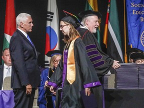 Taylor University student, Laura Rathburn receives her diploma from Taylor University President Paul Lowell Haines as she walks past Vice President Mike Pence, left, during the commencement ceremony Saturday, May 18, 2019 in Upland, Ind. Dozens of graduates and faculty have protested the selection of Vice President Mike Pence as the commencement speaker at Taylor University in Indiana by walking out moments before his introduction.