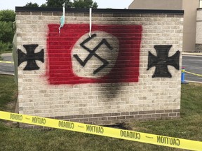 FILE - In this July 30, 2018 file photo, a garbage shed spray painted by vandals with a Nazi flag and iron crosses stands on the grounds of the Congregation Shaarey Tefilla synagogue in the Indianapolis suburb of Carmel, Ind. Nolan Brewer has been sentenced to three years in prison for spray-painting anti-Semitic graffiti and lighting fires outside the synagogue. U.S. Attorney Josh Minkler says the 21-year-old Brewer was sentenced Monday evening, May 21, 2019 for conspiring to violate the civil rights of Congregation Shaarey Tefilla. Minkler announced Tuesday that Brewer pleaded guilty to a federal hate crime.