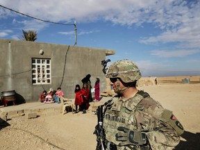 In this Jan. 27, 2018, file photo, U.S. Army soldiers speak to families in rural Anbar on a reconnaissance patrol near a coalition outpost in western Iraq. Iraq’s president has slammed comments by U.S. President Donald Trump who he says he wants to keep U.S. troops in Iraq “to watch Iran.”