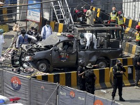 Pakistani security personnel surround a damaged police van in Lahore, Pakistan, Wednesday, May 8, 2019. A powerful bomb exploded near security forces guarding a famous Sufi shrine in Pakistan on Wednesday, police said.