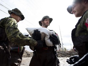 Canadian Forces members build a wall of sandbags at the underpass on Alexander Street to try to keep back floodwaters in Pembroke, Ont., Saturday, May 11, 2019.