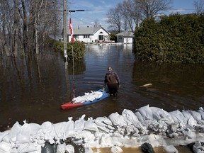 A resident uses a boat to float sandbags to protect her home from flooding on Bayview Drive in the Ottawa community of Constance Bay, on Tuesday, April 30, 2019.