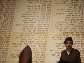An Israeli soldier stands in front of a monument engraved with names of fallen Israeli soldiers, before a ceremony marking Memorial Day in Jerusalem, Tuesday, May 7, 2019.