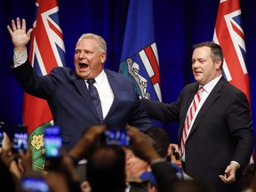 Ontario Premier Doug Ford, left, and United Conservative Leader Jason Kenney greet supporters on stage an anti-carbon tax rally in Calgary, Friday, Oct. 5, 2018.
