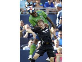 Seattle Sounders defender Roman Torres, top, and Sporting Kansas City defender Seth Sinovic battle for control of the ball during the first half of an MLS soccer match Sunday, May 26, 2019, in Kansas City, Kan.