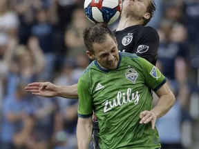 Seattle Sounders forward Harrison Shipp (19) and Sporting Kansas City defender Seth Sinovic, top, battle to control the ball during the second half of an MLS soccer match Sunday, May 26, 2019, in Kansas City, Kan.