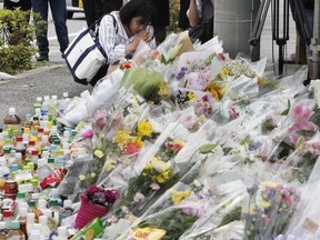 A woman prays for victims at the scene where a knife attack took place in Kawasaki near Tokyo Wednesday, May 29, 2019. A man carrying a knife in each hand and screaming "I will kill you!" attacked a group of schoolgirls near a school bus parked at a bus stop just outside Tokyo on Tuesday, officials said.