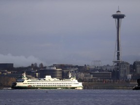 FILE - In this Dec. 27, 2018, file photo, a Washington State ferry heading into Elliott Bay is illuminated by the sun as the city behind remains under clouds in Seattle.. Authorities say a Washington State ferry struck a whale Tuesday night, May 28, 2019, during a sailing from Seattle to Bainbridge Island.