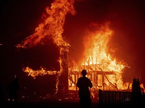 FILE - In this Nov. 8, 2018 file photo a home burns as the Camp Fire rages through Paradise, Calif. California fire authorities say that Pacific Gas and Electric equipment was responsible for the deadliest and most destructive wildfire in state history. Cal Fire said in a press release issued Wednesday, May 15, 2019, that electrical transmission lines in the Pulga area sparked the Nov. 8 fire that wiped out most of the town of Paradise and killed 85 people.