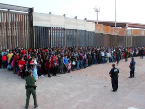 This May 29, 2019 photo released by U.S. Customs and Border Protection (CBP) shows some of 1,036 migrants who crossed the U.S.-Mexico border in El Paso, Texas, the largest that the Border Patrol says it has ever encountered. Video shows them going under a chain-link fence to the U.S., where they waited for agents to come. The Border Patrol has encountered 180 groups of more than 100 people since October, compared to 13 during the previous 12-month period and two the year before. (U.S. Customs and Border Protection via AP)