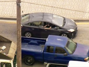 In this photo from video provided by FOX11 Los Angeles shows a man leaning out the window of a moving car, shooting at pursuing police vehicles during a wild car chase in the Los Angeles area Friday afternoon, May 10, 2019. The car finally came to a halt in the Los Angeles suburb of Vernon, where the woman driver, who had blood on her shirt, surrendered. The gunman remained inside the car. (FOX11 Los Angeles via AP)