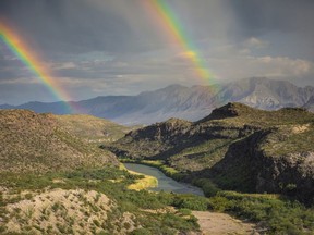 This December, 2017 photo released by Fin and Fur Films shows a double rainbow over Big Bend National Park, Texas, and the Rio Grande along the U.S.-Mexico border, with Mexico being on the right side of the river. The new documentary, "The River and The Wall", released Friday, May 3, 2019, examines the diverse wildlife and landscape of the Rio Grande along the U.S.-Mexico border. (Fin and Fur Films via AP)
