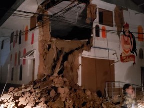 In this photo provided by Firefighters of Peru, people pass in front destroyed wall in Yurimaguas Peru, Sunday, May 26, 2019. A powerful magnitude 8.0 earthquake struck the Amazon jungle in north-central Peru early Sunday, the U.S. Geological survey reported, collapsing buildings and knocking out power to some areas. (Firefighters of Peru via AP)