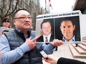 Louis Huang of Vancouver Freedom and Democracy for China holds photos of Canadians Michael Spavor and Michael Kovrig, who are being detained by China, in Vancouver on March 6, 2019.