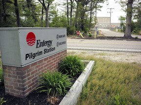 A sign featuring an Entergy Corp. logo is attached to a sign near a gate to the Pilgrim Nuclear Power Station, in Plymouth, Mass., Tuesday, May 28, 2019. The operators of the nuclear plant performed a simulated shutdown at a training facility several miles from the reactor Tuesday, in advance of the actual shutdown of the aging reactor planned for Friday, May 31.