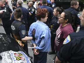 A pair of Hopkins students are arrested after blocking a police van carrying fellow protestors, Wednesday, May 8, 2019. Baltimore police arrested seven people as they ended a monthlong sit-in in the lobby of an administrative building at Johns Hopkins University, where protesters have demonstrated against the creation of a campus police force and the institution's contracts with the U.S. Immigrations and Customs Enforcement agency.
