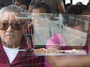 In this May 15, 2019 photo shot through a window, passengers ride a public transit bus through the Iztapalapa borough of Mexico City. Vicious armed robberies have gotten so common aboard buses in Mexico City that commuters have come up with a clever if disheartening solution: Many are buying fake cellphones, to hand over to thieves instead of their real smartphones.