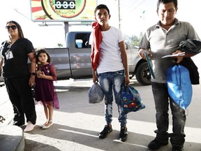 Guatemalan asylum seekers, a father (R) and son (C), hold their belongings as they prepare to board a bus to meet their sponsors in Las Vegas, after leaving a shelter for migrants who seek asylum, on May 16, 2019 in Las Cruces, New Mexico.