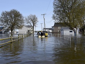 In this Wednesday, May 8, 2019 photo, Estral Beach Firefighters Courtney Millar, right, Eric Bruley, and Chase Baldwin pull the Estral Beach fire boat with Chief Dave Millar down Lakeshore Dr. in the south end of Estral Beach in Berlin Township, Mich., to see if anyone needs to be evacuated while also checking the floodwaters. Wind-driven water caused more flooding in southeastern Michigan along western Lake Erie following recent rainfall that contributed to high water levels in the Great Lakes .