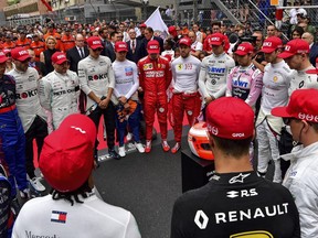 The drivers clap hands around a red helmet on a podest, reading 'Thank you Niki', during a minute of silence to tribute F1 legend Niki Lauda prior the Monaco Formula One Grand Prix race, at the Monaco racetrack, in Monaco, Sunday, May 26, 2019. The former F1 champion Niki Lauda died last week.