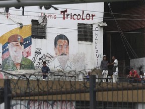 Youth hang out next to a mural featuring the late President Hugo Chavez and his successor Nicolas Madro, at the Petare shantytown, in Caracas, Venezuela, Wednesday, May 8, 2019. Venezuela has been in sharp decline for years, suffering from hyperinflation and shortages of food and medicine.