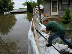 Alley Ringhausen uses sandbags to shore up the wall he and other volunteers built around the Riverview House in Elsah, Ill., as floodwater from the Mississippi River seeps through a makeshift barrier on Monday, May 6, 2019.