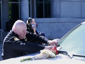 Biloxi Police Chief John Miller places flowers and a card on the police SUV of Officer Robert McKeithen, outside the station in Biloxi, Miss., Monday, May 6, 2019. McKeithen was killed in the line of duty outside the Biloxi Police Department, Sunday night. A manhunt is underway to find the suspect, who shot McKeithen multiple times, police say.