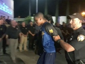 In this Monday, May 6, 2019 image taken from video, shooting suspect Darian Tawan Atkinson is lead into a police station in Biloxi, Miss. Police on Mississippi's Gulf Coast captured Atkinson, a suspect in the slaying of a uniformed officer gunned down outside a Biloxi police station, concluding a tense manhunt. (The Clarion-Ledger via AP)