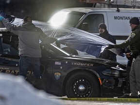 FILE - In this March 15, 2019 file photo, law enforcement officers cover Montana State Trooper Wade Palmer's patrol car at the scene of the shooting near the Evaro Bar in Missoula, Mont. The wife of trooper Palmer, who is recovering from a traumatic brain injury after being shot three times, is thanking the medical team who gave them "the fighting chance we needed to get through this." Lindsey Palmer made her emotional comments Wednesday, May 22, 2019, at the University of Utah Health in Salt Lake City shortly before her husband was to be released from the hospital and flown back home.